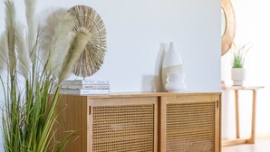 A wooden cabinet with woven doors, a potted plant, and decorative items on top. - Blue Cottage Bruny Island (Alonnah)