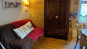 A cozy room with a red sofa, wooden wardrobe, and a painting of reindeer on the wall.