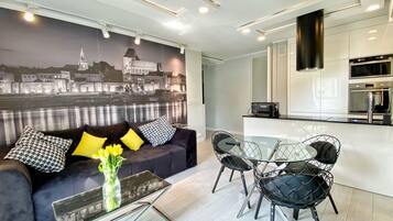 A modern living room with a sofa, a glass coffee table, and a dining area with chairs and a glass table.