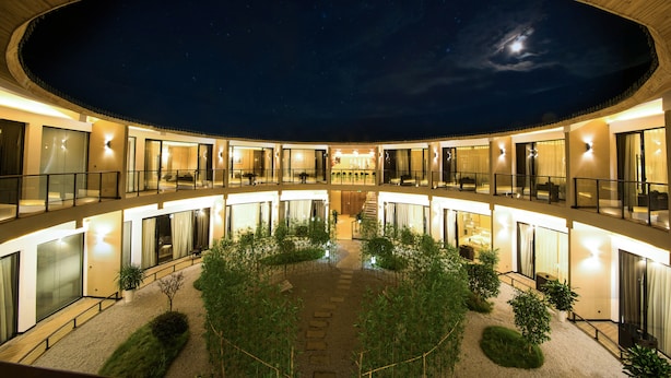 Un hotel moderno con un patio central, varios balcones y grandes ventanales.