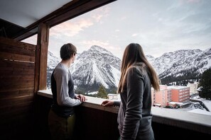 Una habitación con interior de madera y un amplio ventanal con vistas a un paisaje montañoso nevado.