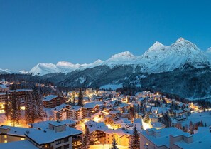 A snow-covered mountain town at dusk with illuminated buildings and a view of snow-capped peaks. - Arosa Mountain Lodge (Arosa)