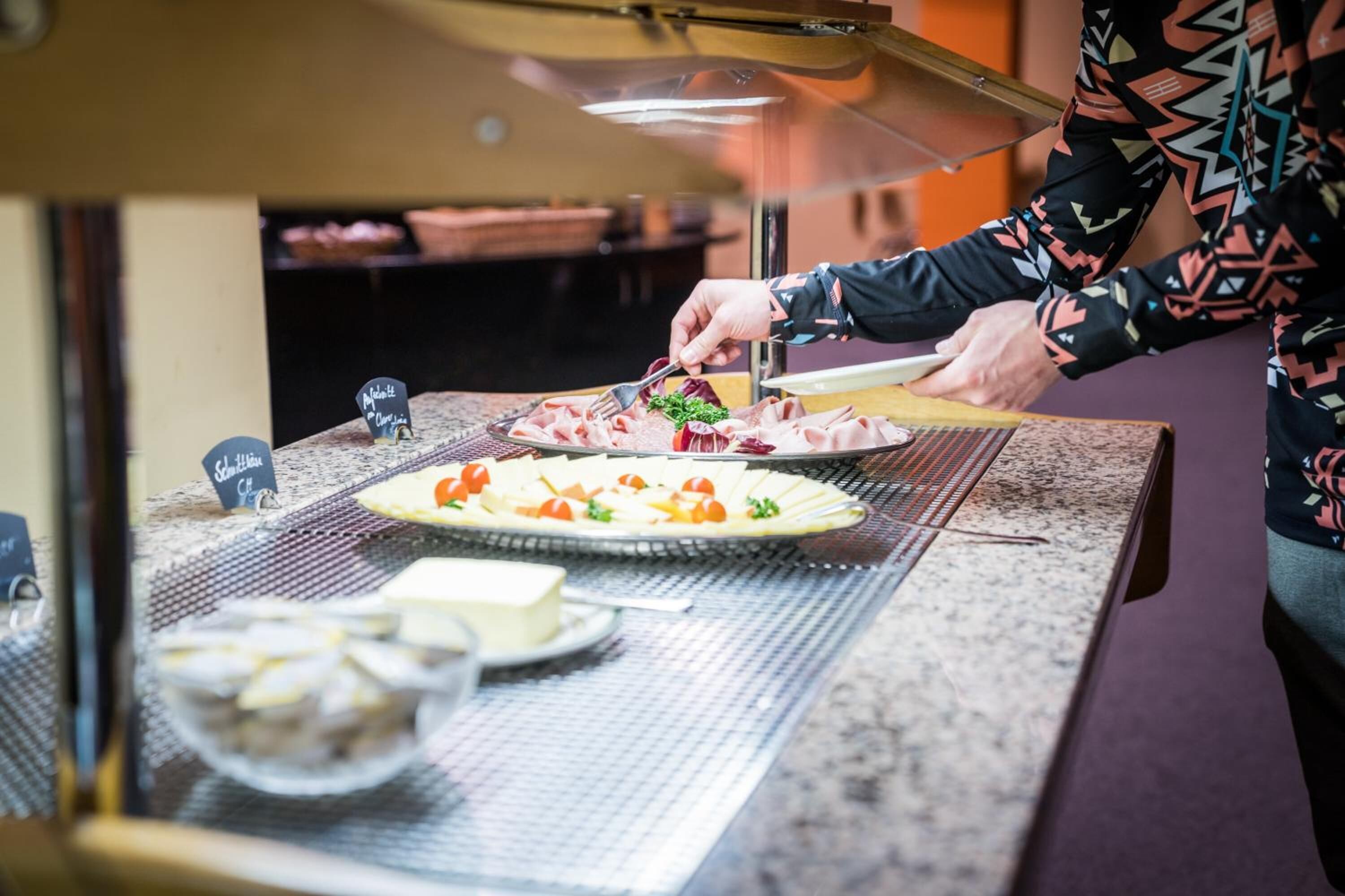 Una persona preparando comida en una barra con diferentes platos e ingredientes.