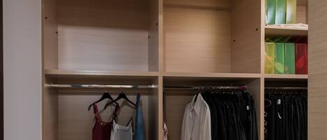A walk-in closet with multiple shelves, hanging space, and drawers.
