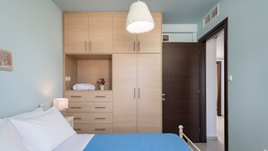 Ein Schlafzimmer mit einem Bett, einem Kleiderschrank, einem Nachttisch und einer Pendelleuchte.