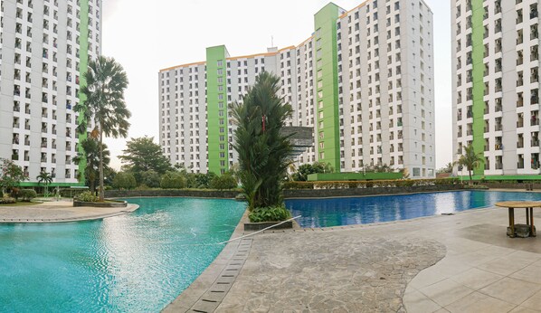A residential complex with high-rise buildings, a swimming pool, and surrounding greenery.
