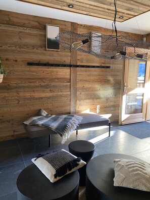 A modern interior with a wooden wall, a sofa, a round table, and a hanging light fixture.