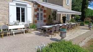 Un bâtiment en pierre doté d’un patio couvert, d’un espace extérieur aménagé pour s’asseoir et d’un chemin de gravier.