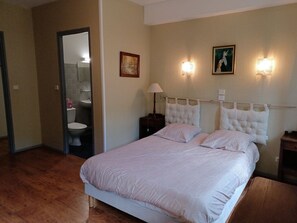 Un dormitorio con una cama grande, una mesita de noche, una lámpara de pared y un cuadro.