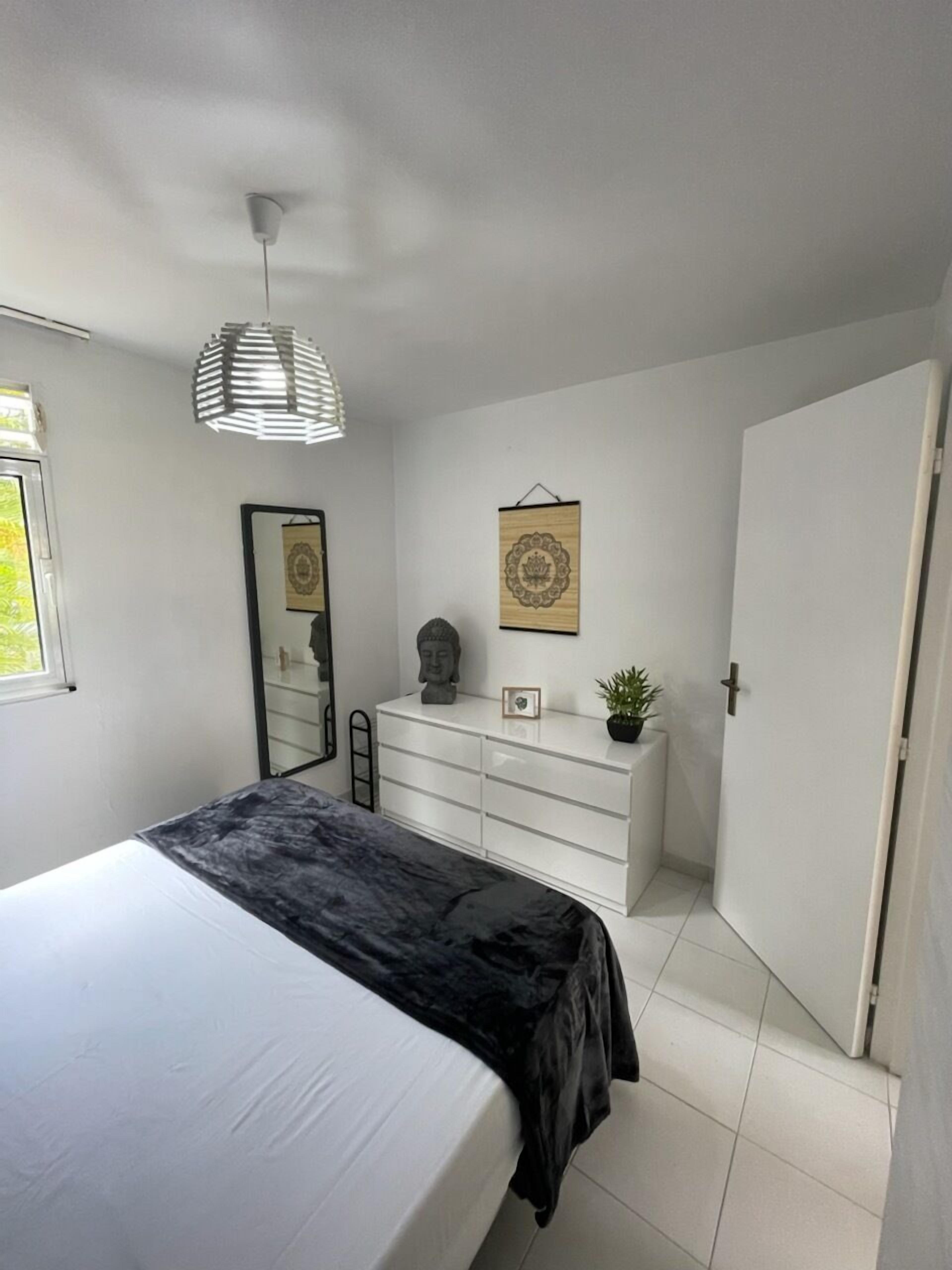 A bedroom with a bed, a dresser, a mirror, and a door.