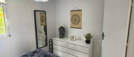 A bedroom with a bed, a dresser, a mirror, and a door.