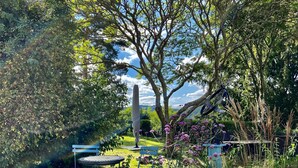 A garden with a table and chairs, surrounded by various plants and a large tree. - Exceptional vacation home in a fantastic location above Rheinfels Castle, Loreley (Sankt Goar)