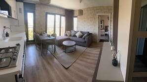 A compact living space with a kitchenette, a dining area, a sofa, and a small round table. - Aden Life (Ankara)