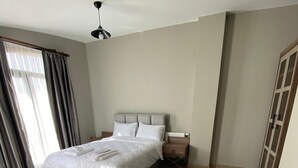 A bedroom with a bed, bedside tables, a rug, and a wardrobe. - Aden Life (Ankara)