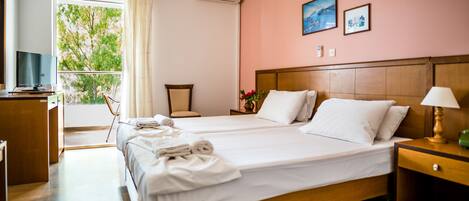 A hotel room with two beds, a desk, a chair, and a window with curtains.