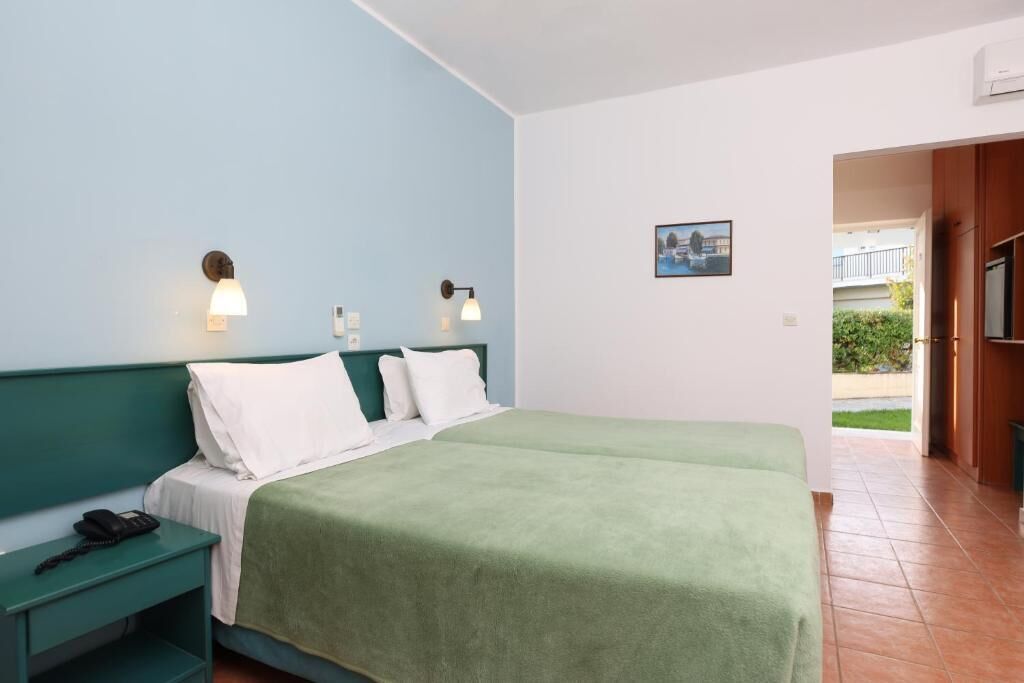 A hotel room with a bed, bedside tables, and a view of the outside.