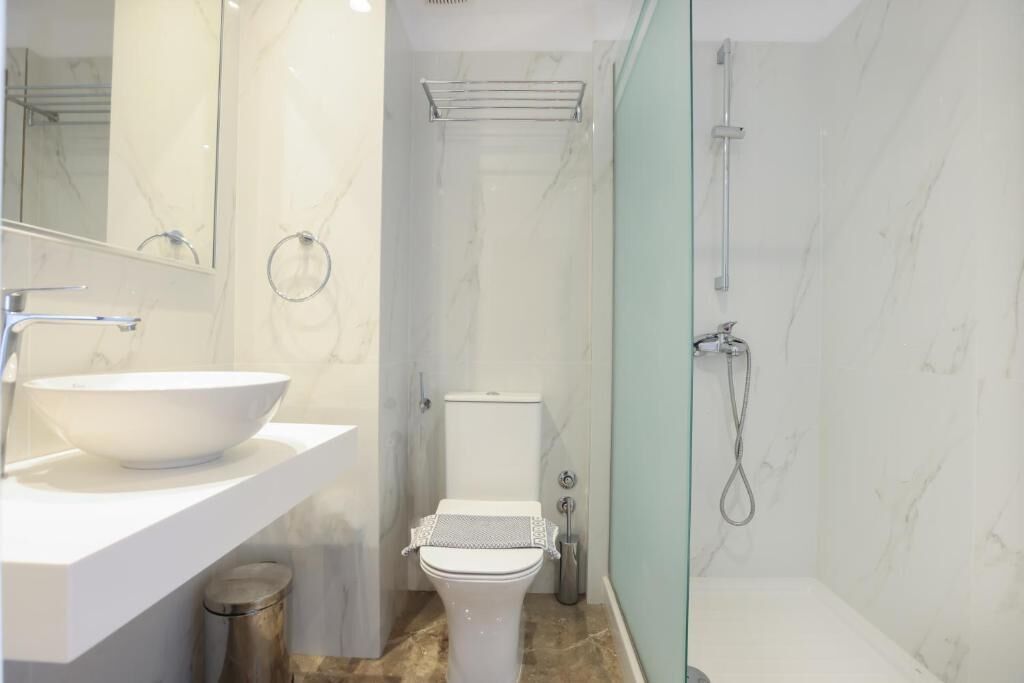 Een moderne badkamer met een wit wastafel, toilet en douche.