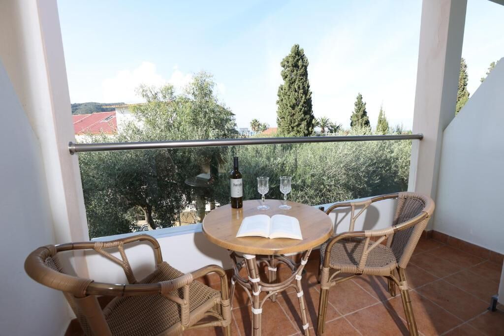 A balcony with wicker chairs, a round table, and a bottle of wine.