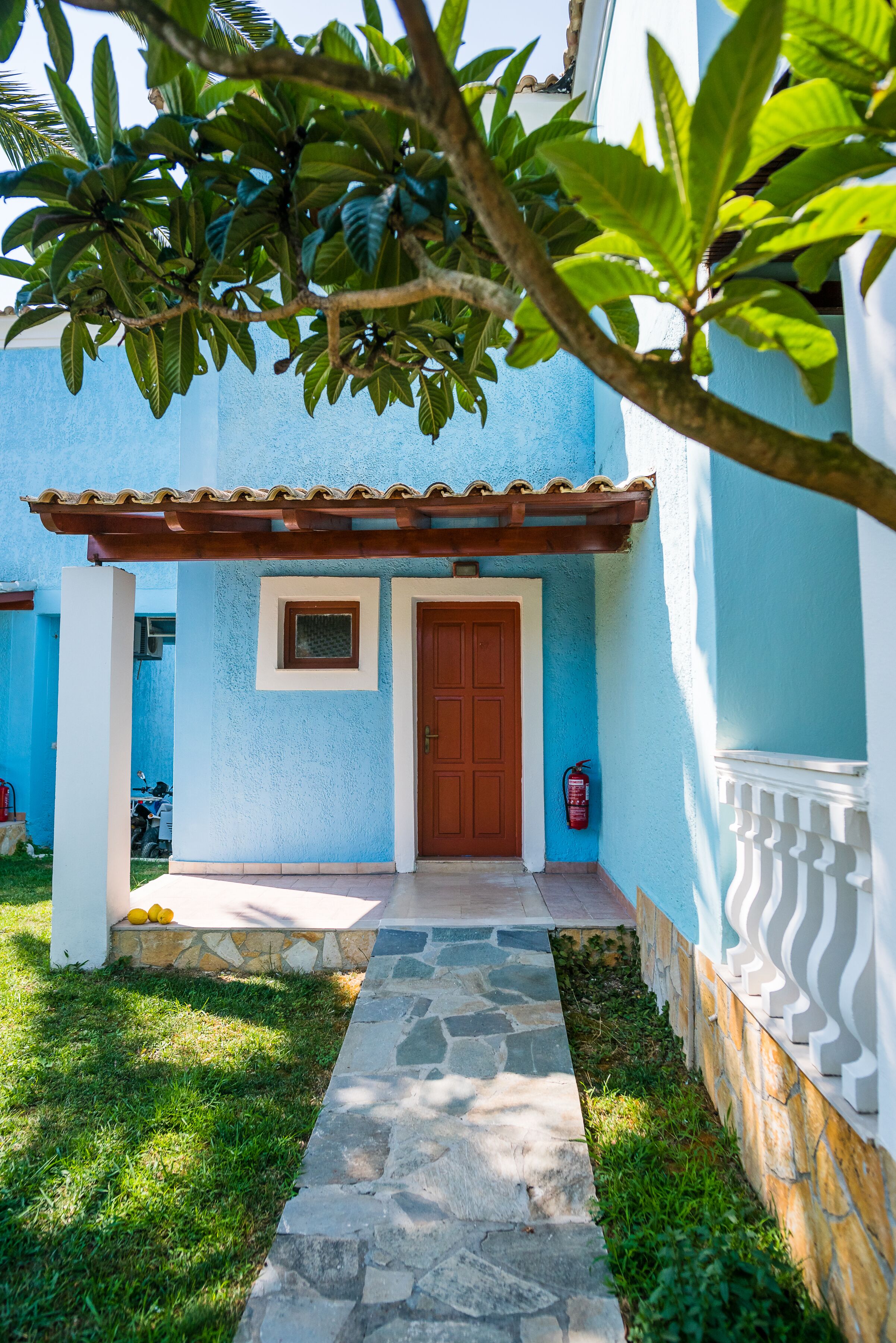 Un bâtiment bleu avec un chemin de pierre menant à une porte en bois.