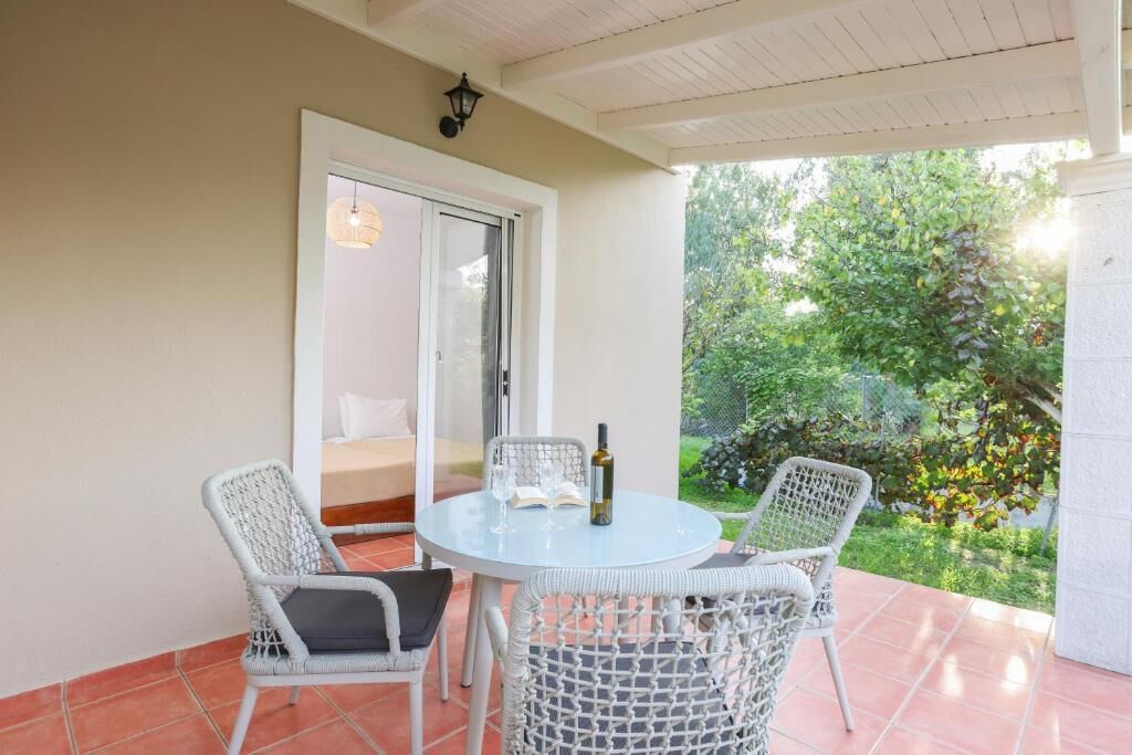 A patio with a round table and two wicker chairs, a bottle, and glasses on the table.