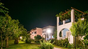 Un edificio residencial bien iluminado con jardín, un sendero y un balcón.