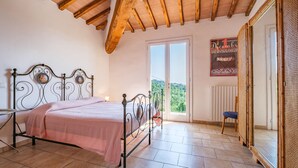 A bedroom with a bed, a chair, a window, and a door. - COUNTRY FAMILY VILLA 10 BEDS WITH PRIVATE POOL (CASTELLINA MARITTIMA PISA)