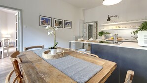 Una cocina moderna con una mesa de comedor de madera, sillas e iluminación colgante.