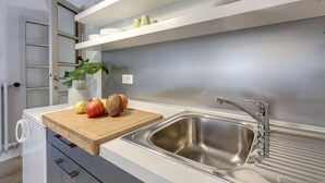 Una cocina moderna con un lavamanos de acero inoxidable, encimera de madera y armarios blancos.