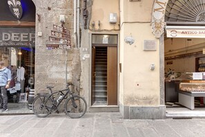 Une vue de rue avec un vélo garé contre un bâtiment, une devanture de magasin portant l’enseigne « ANTICO SALONE », et un panneau indicateur avec des flèches directionnelles.