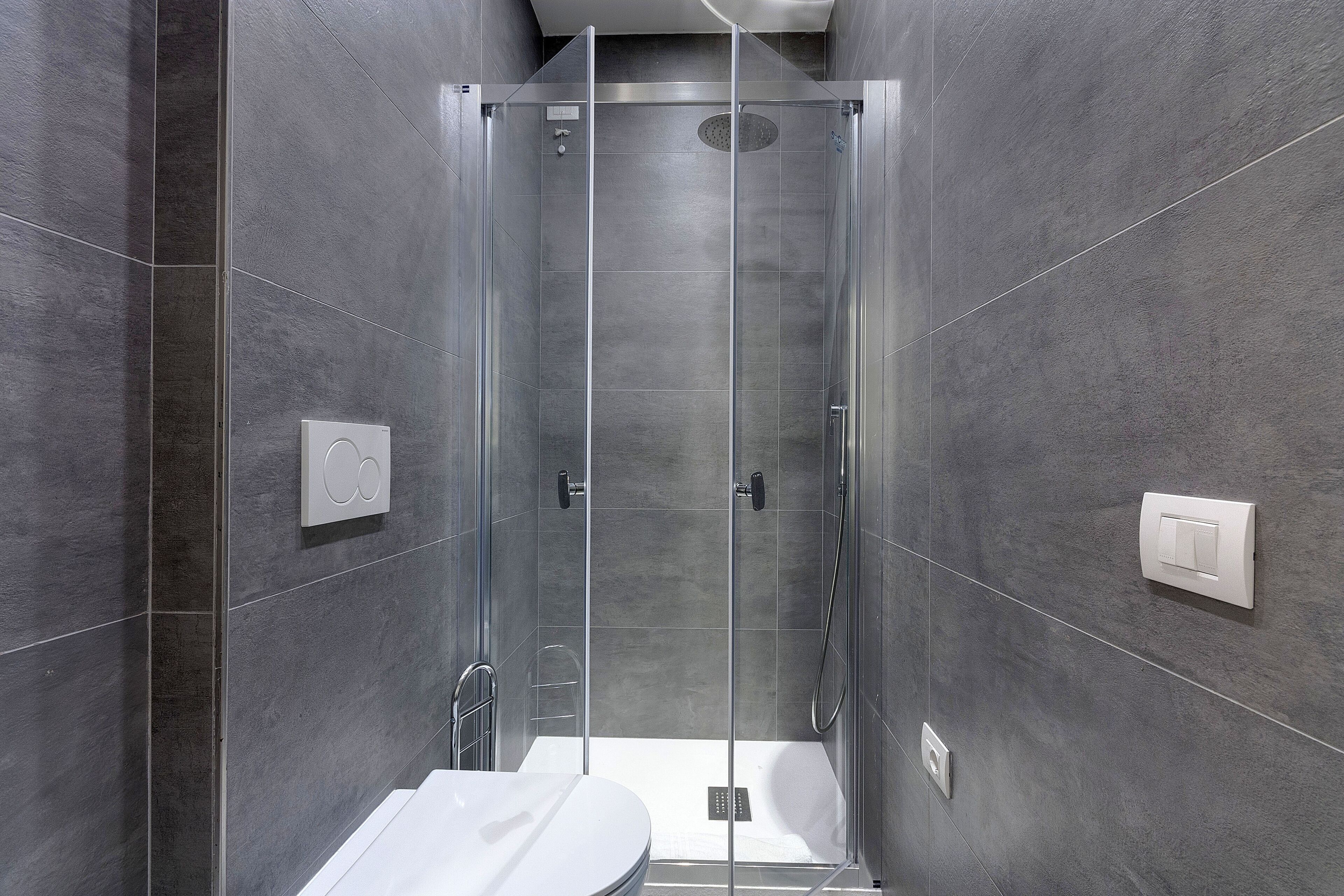 Une salle de bain moderne avec une douche à parois de verre, un lavabo blanc et des toilettes.