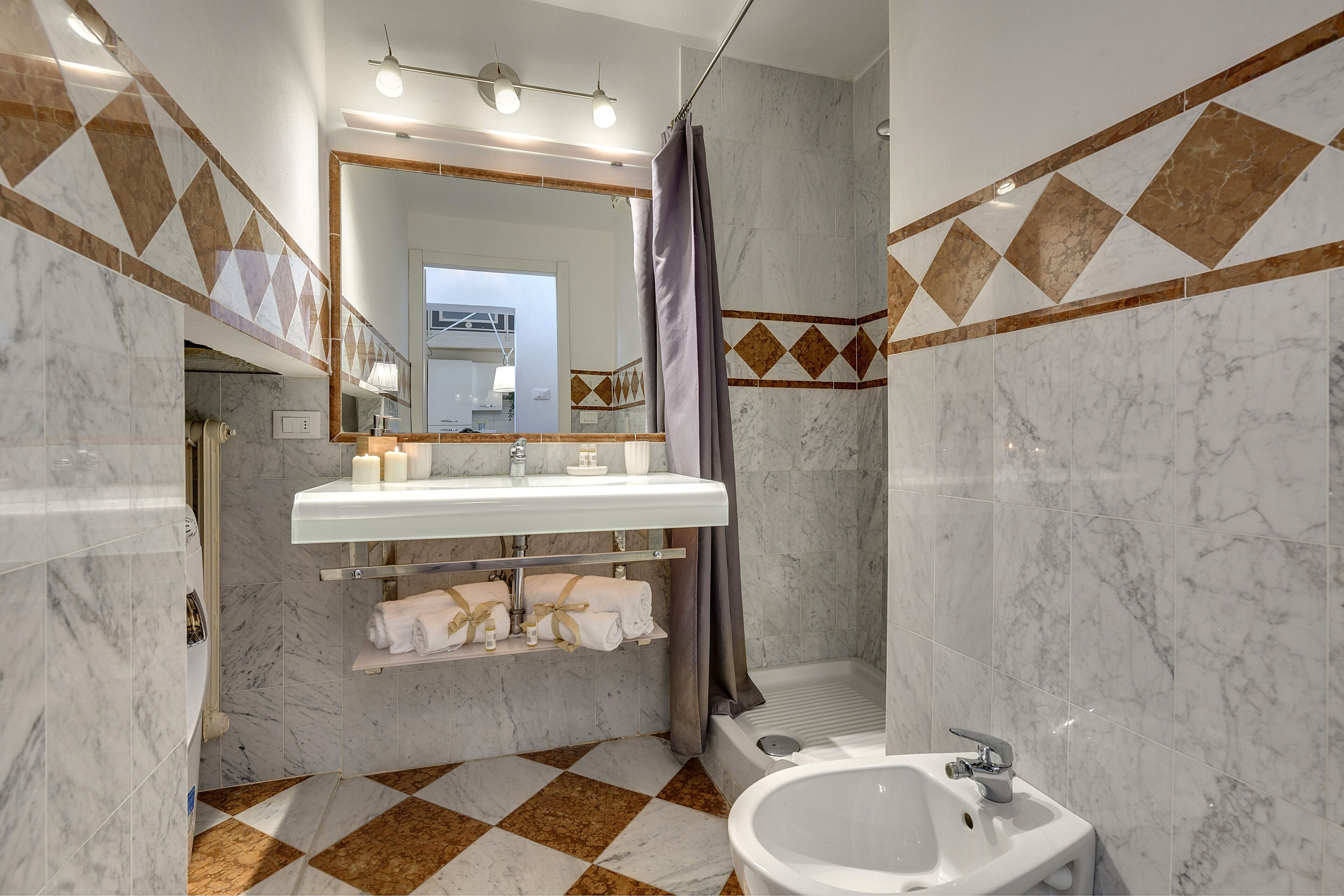 Un baño moderno con lavamanos, espejo y bañera blancos.