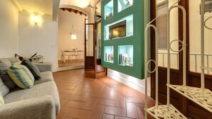 A living room with a sofa, a green wall with shelves, and a wooden staircase. - Mamo Florence - Tegolaio Apartment (Florence)