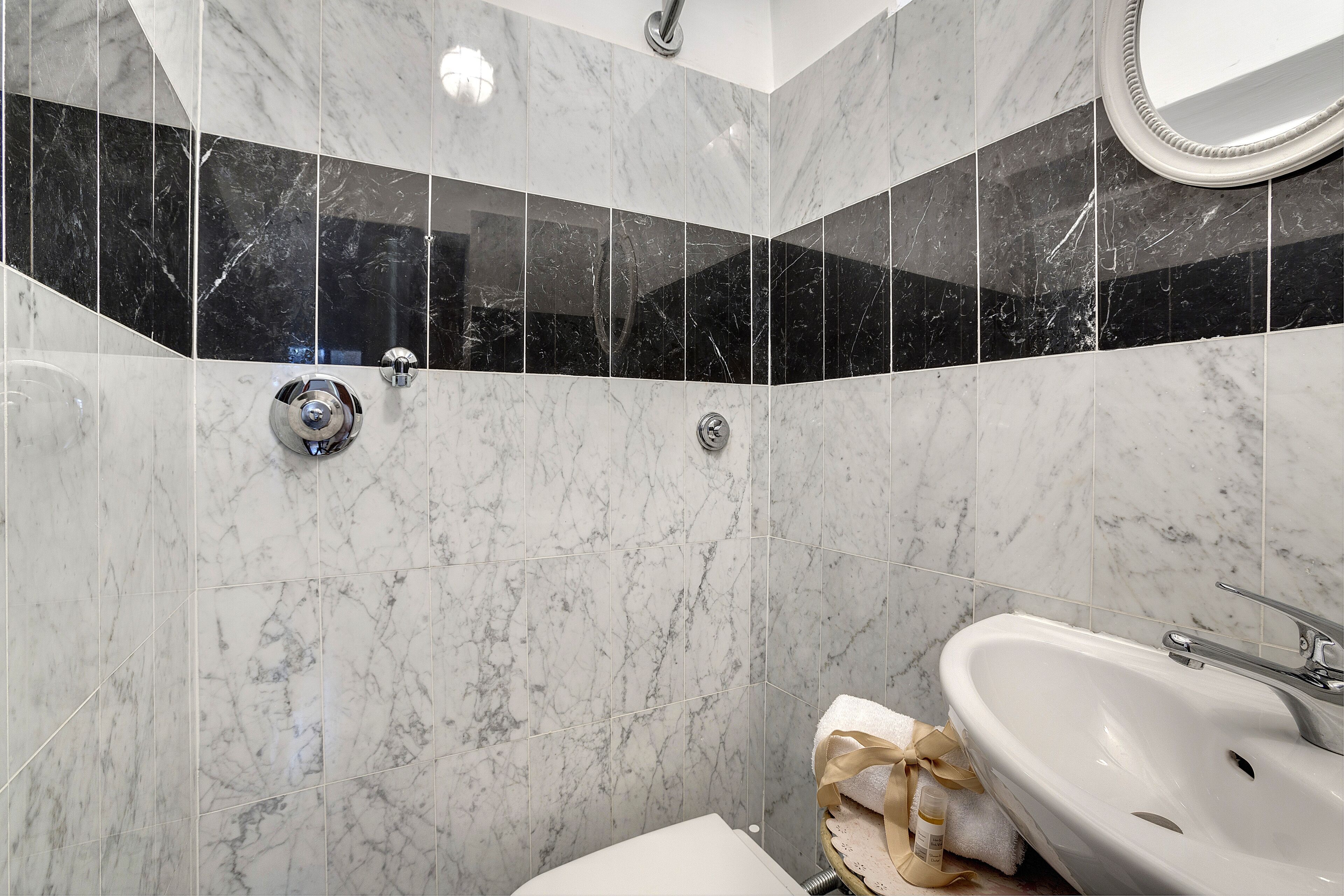 A bathroom with a white sink, a mirror, and a shower with a chrome faucet.