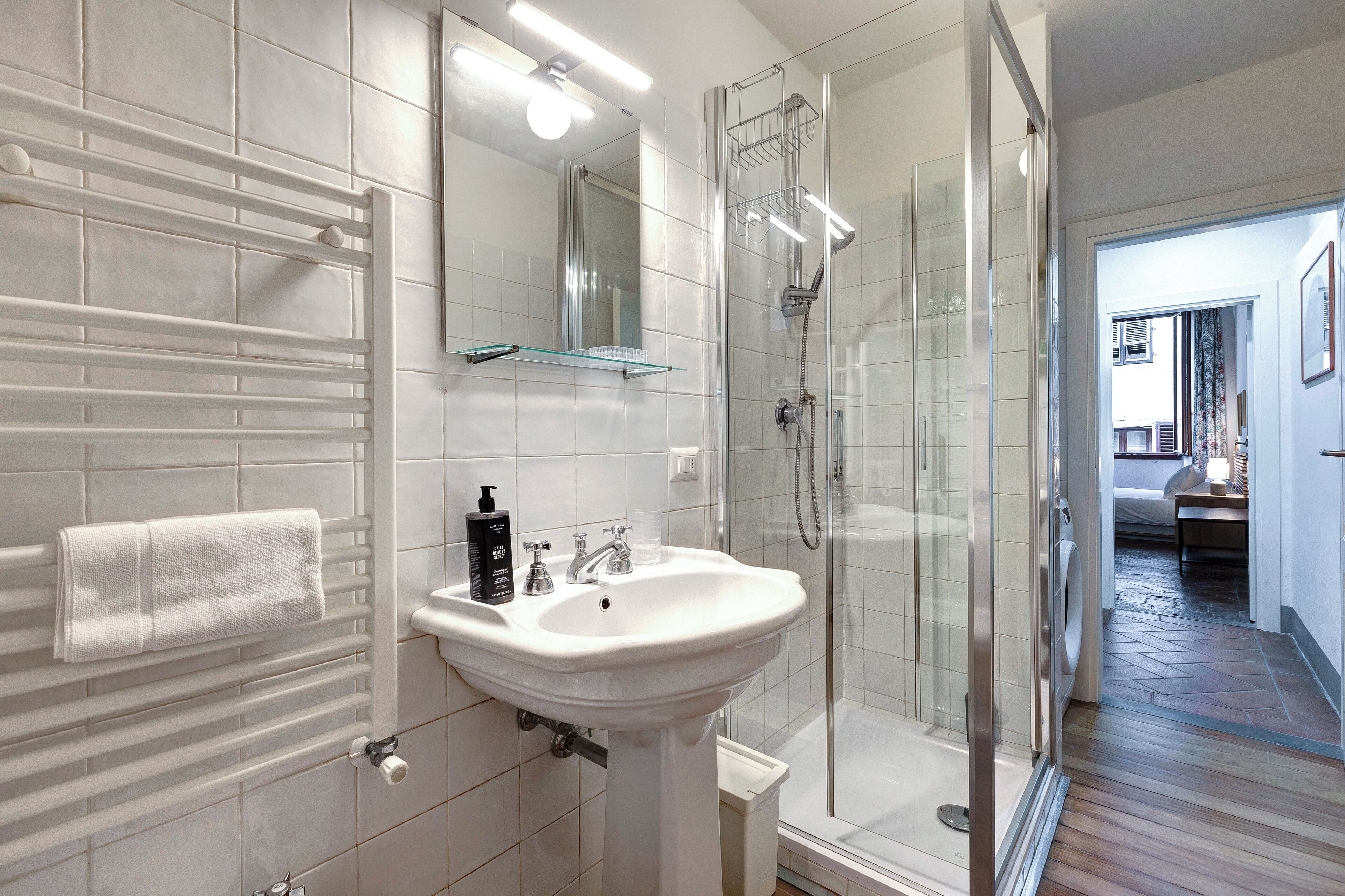 A modern bathroom with a white sink, mirror, and glass shower enclosure.