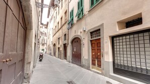 Una calle estrecha flanqueada por edificios, con una motocicleta a lo lejos.