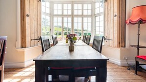A dining area with a large wooden table, six chairs, and a vase with flowers. - St Anne's House, Sea Views, 7 Bedrooms - Sleeps 30 (Plymouth)
