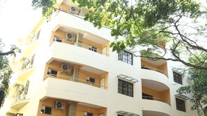 A multi-story building with balconies, air conditioning units, and a sign indicating a restaurant. - Karma Palace (Bangalore)