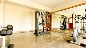 A gym with various exercise equipment, a large mirror, and a polished marble floor. - Karma Palace (Bangalore)