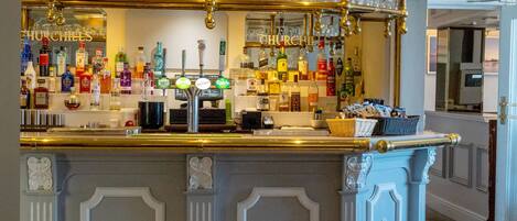 A bar area with a counter, various bottles, glasses, and a cash register.