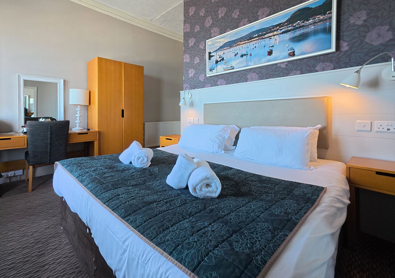 Ein Hotelzimmer mit einem großen Bett, einem Schreibtisch, einem Stuhl und einem Kleiderschrank.