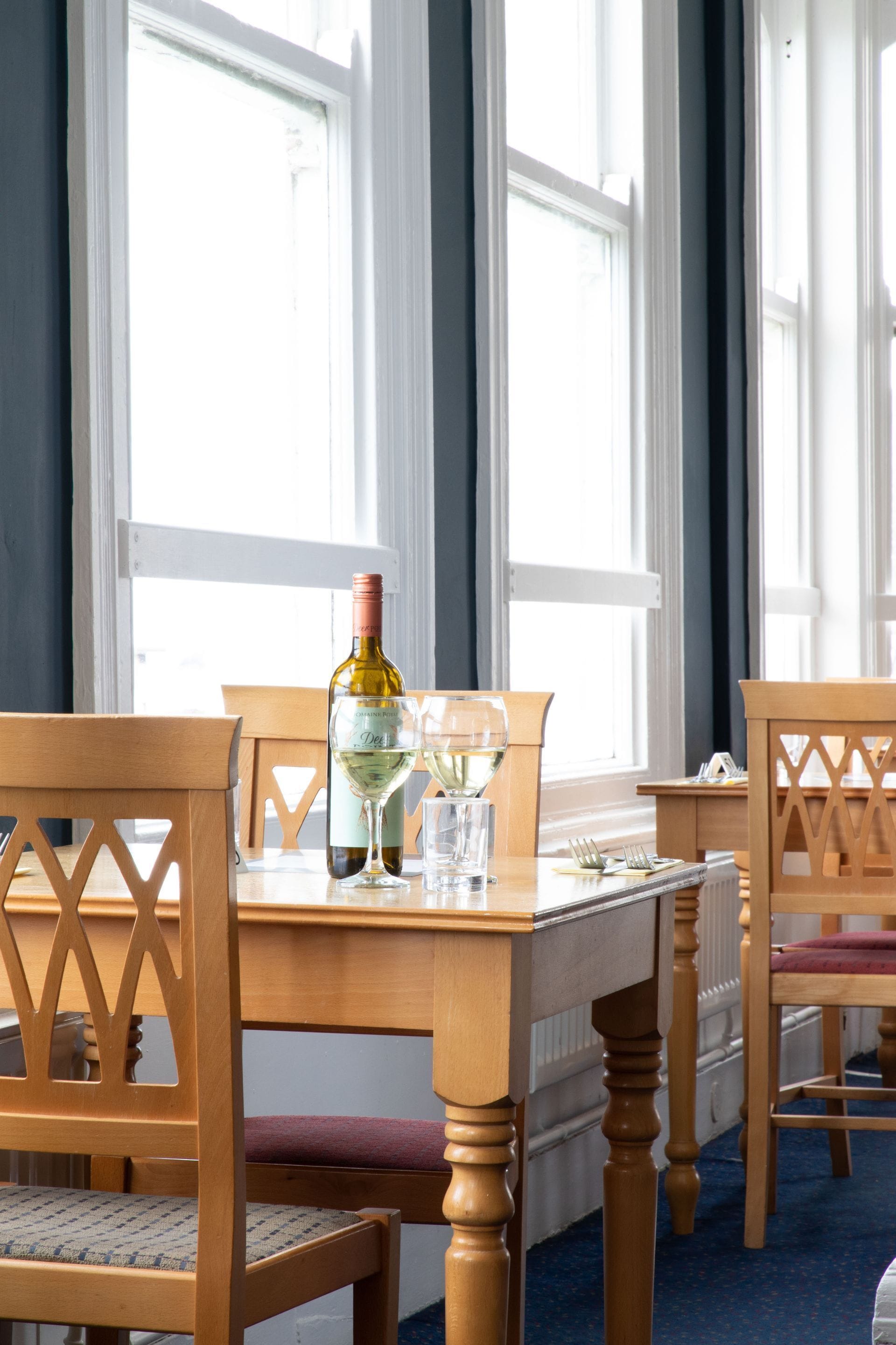 A dining table with chairs, a bottle of wine, and glasses.