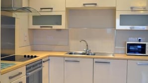 A modern kitchen with white cabinets, a stainless steel range hood, a microwave, and a dishwasher.