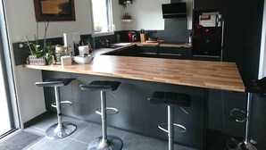 Cozinha moderna com bancada de madeira, banquetas pretas e uma ilha grande.