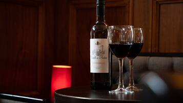 Uma garrafa de vinho e dois copos sobre uma mesa com uma vela ao fundo.