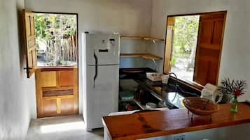 Een koelkast, een oven, een kookplaat, kookgerei, borden en bestek