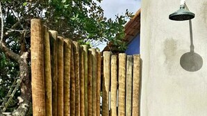 Una valla de bambú con un muro de concreto y una lámpara de metal.
