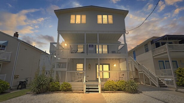 A two-story beachfront house with a balcony, a front porch, and a staircase leading to the entrance. - 2 Bd Beach Condo only 2 min walk to OC's Goldcoast (Ocean City)