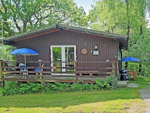 A wooden cabin with a deck, two blue umbrellas, and a sign reading 'Torwood Four.' - 3 bedroom accommodation in Cenarth, near Newcastle Emlyn (Cenarth, near Newcastle Emlyn)