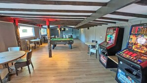 Une pièce équipée d’une table de billard, d’une table de snooker et d’un flipper.