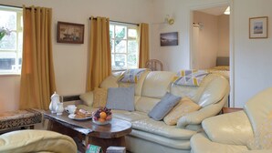Un salon avec un canapé, des fauteuils, une table basse et une fenêtre avec des rideaux.